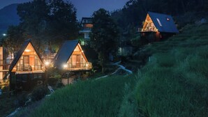 A row of cozy, triangular-roofed cabins nestled in a forested hillside at night. - Yichun Old Yu Xinzhi Homestay (Yichun)