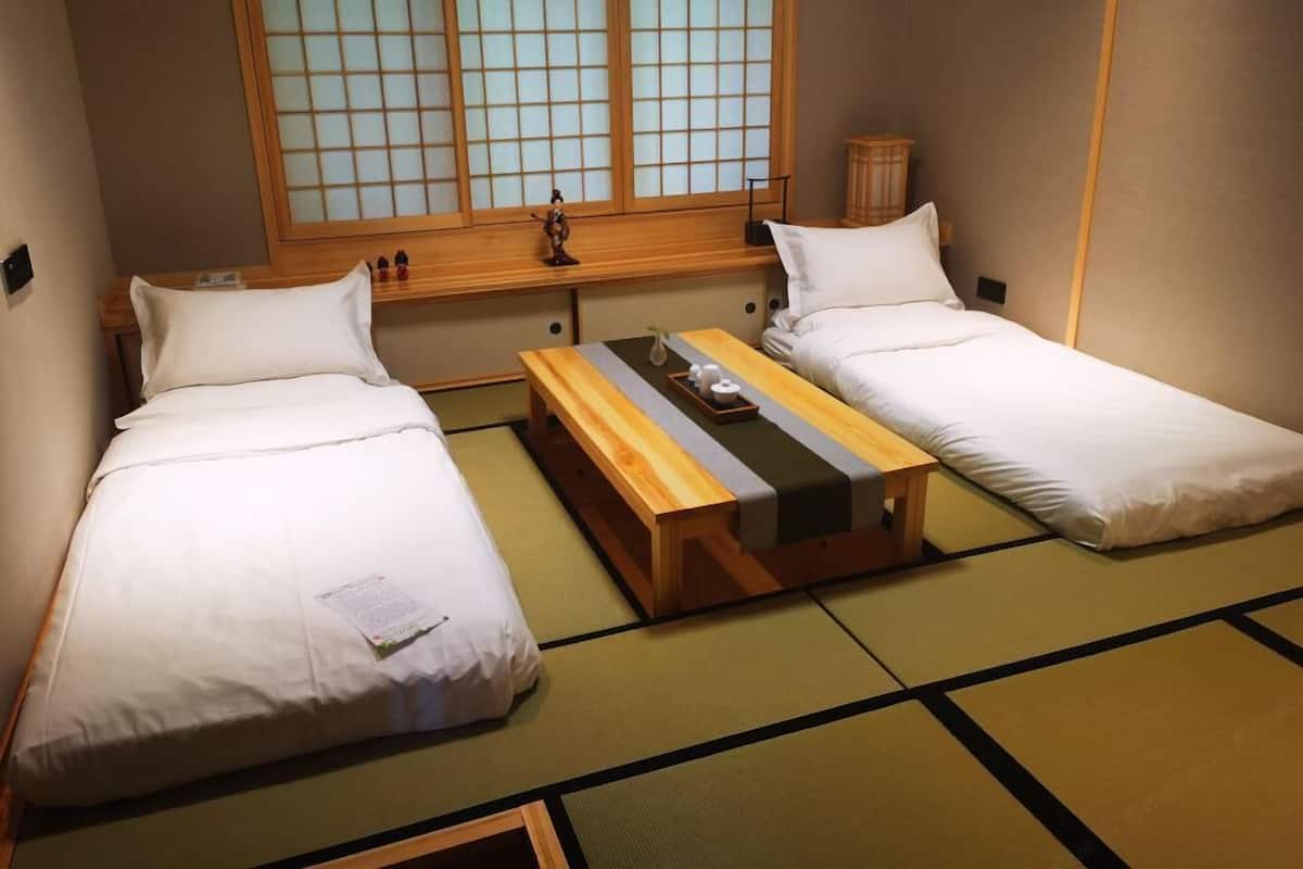 A traditional Japanese-style room with two tatami mat beds, a wooden table with a tray, and a shoji screen window.