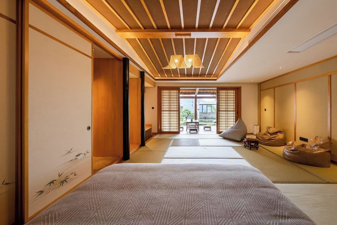 A traditional Japanese-style room with tatami flooring, a low ceiling with wooden beams, and sliding doors.