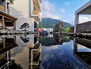 A modern building with a reflective pool, a traditional stone bridge, and a mountainous backdrop. - Yichun Old Yu Xinzhi Homestay (Yichun)