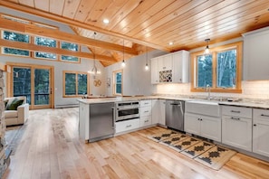 Una cocina amplia con vigas de madera, ventanas grandes y electrodomésticos modernos.