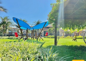 A park with a swing set, a hammock, and a blue structure. - Mandara Lanai Resort (Aquiraz)