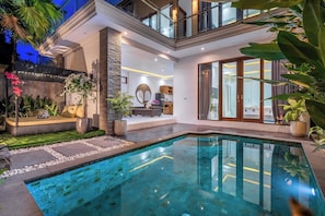 Une maison moderne dotée d’une piscine, d’un balcon et d’un intérieur bien éclairé.