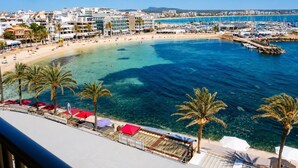 Un hôtel en bord de mer offrant une vue sur la plage, un port de plaisance et une mer d’un bleu limpide.