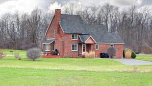 Een huis van rode baksteen met een steil dak, een schoorsteen en een veranda.