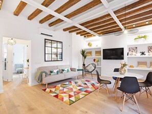En moderne stue med træloft, sofa, sofabord og et spiseområde med stole.