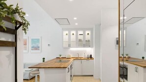 A modern kitchen with white cabinets, a wooden countertop, and a herringbone floor pattern.
