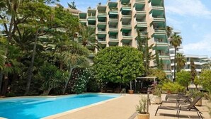 A hotel with a swimming pool surrounded by lush greenery and palm trees.