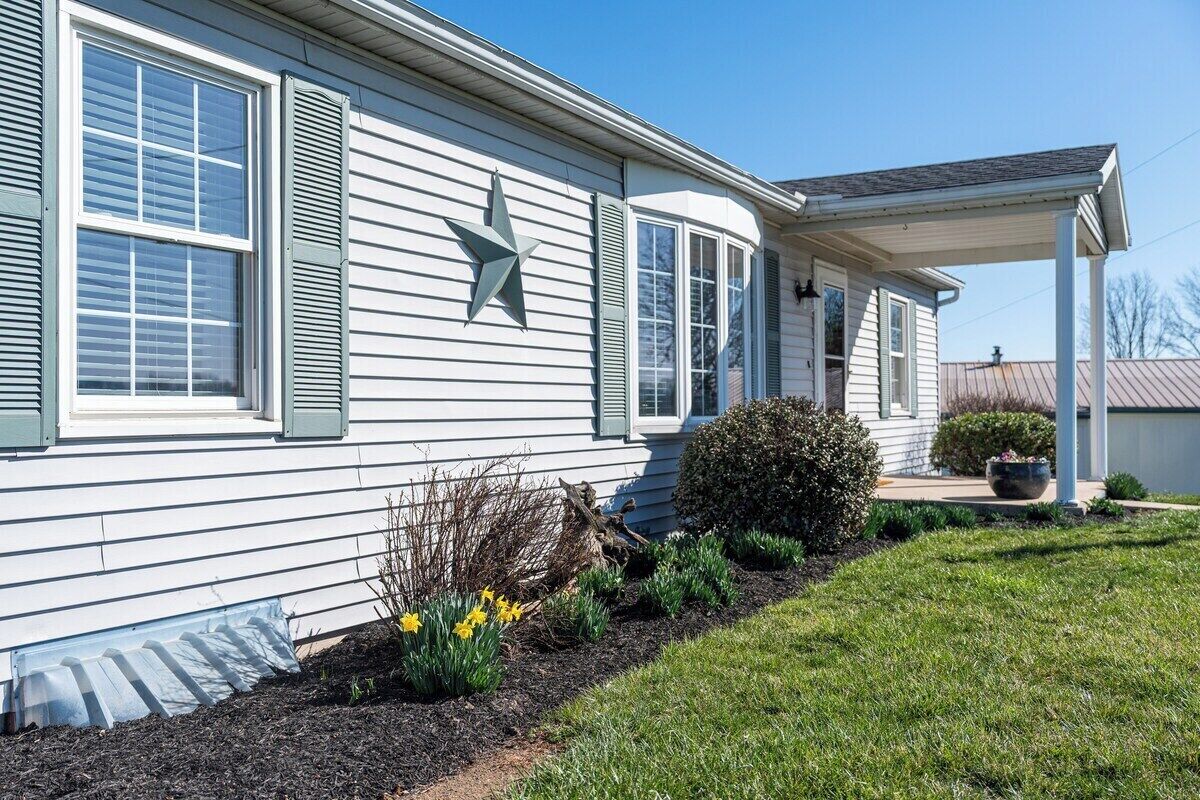 A single-story house with a covered porch, a star decoration on the wall, and a garden with daffodils.