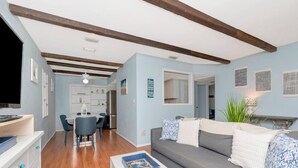 A modern living room with a grey sofa, a coffee table, and a dining area with a white table and chairs. - The Largo Coastal Cottage (Largo)