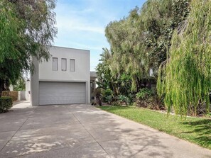 A modern two-story house with a garage, surrounded by lush greenery and trees. - Peppermint Paradise—Seaside Comfort & Home Theatre (Dunsborough)