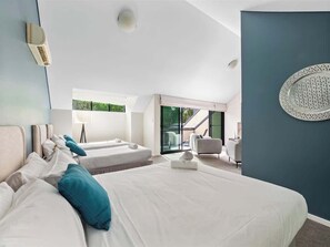 A modern hotel room with a large bed, a smaller bed, a seating area, and a view of the outdoors.