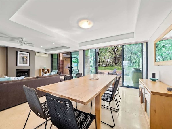 Un salon moderne avec un coin repas, de grandes fenêtres et une cheminée.