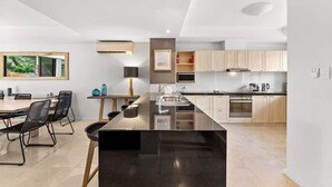 Una cocina moderna con una isla central, armarios de madera y una zona de comedor con mesa y sillas.