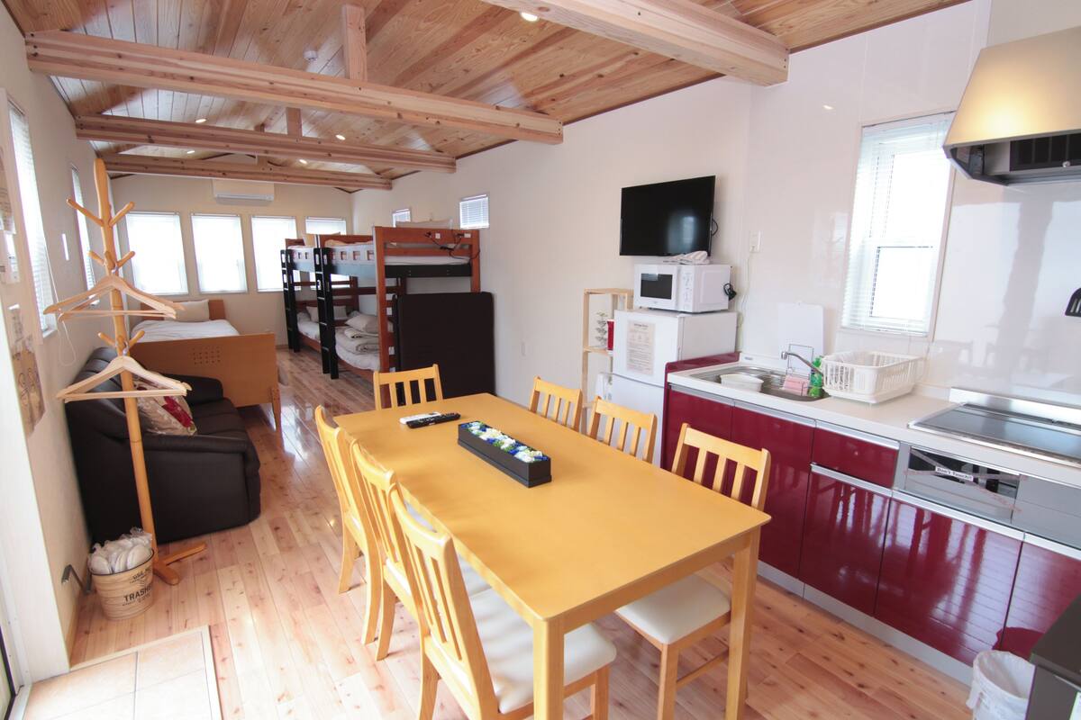A compact kitchen with a wooden table and chairs, a microwave, and a sink.