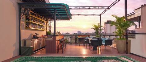 A rooftop bar with a pool, bar area, and seating.