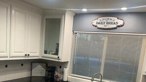 A modern kitchen with white cabinetry, a black countertop, a stainless steel dishwasher, and a window with blinds. - Relax in Clovis and Enjoy The Stay (Clovis)