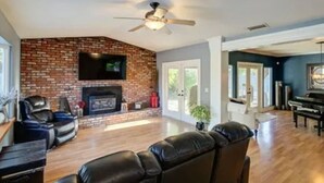 A spacious living room with a brick fireplace, leather sofas, and a ceiling fan. - Relax in Clovis and Enjoy The Stay (Clovis)