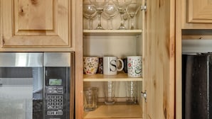 A kitchen with wooden cabinets, a microwave, a refrigerator, and shelves with glassware and mugs. - Convenient 3BR with King Beds Near Hill AFB and Davis Conference Center (Layton)