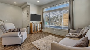 A modern living room with two sofas, a television, and a large window with blinds. - Convenient 3BR with King Beds Near Hill AFB and Davis Conference Center (Layton)