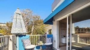 A balcony with a patterned umbrella, a chair, and a table. - Capitola Sands (Capitola)