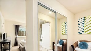 A modern living room with a sofa, a chair, and a TV. There is a sliding glass door leading to another room. - Capitola Sands (Capitola)