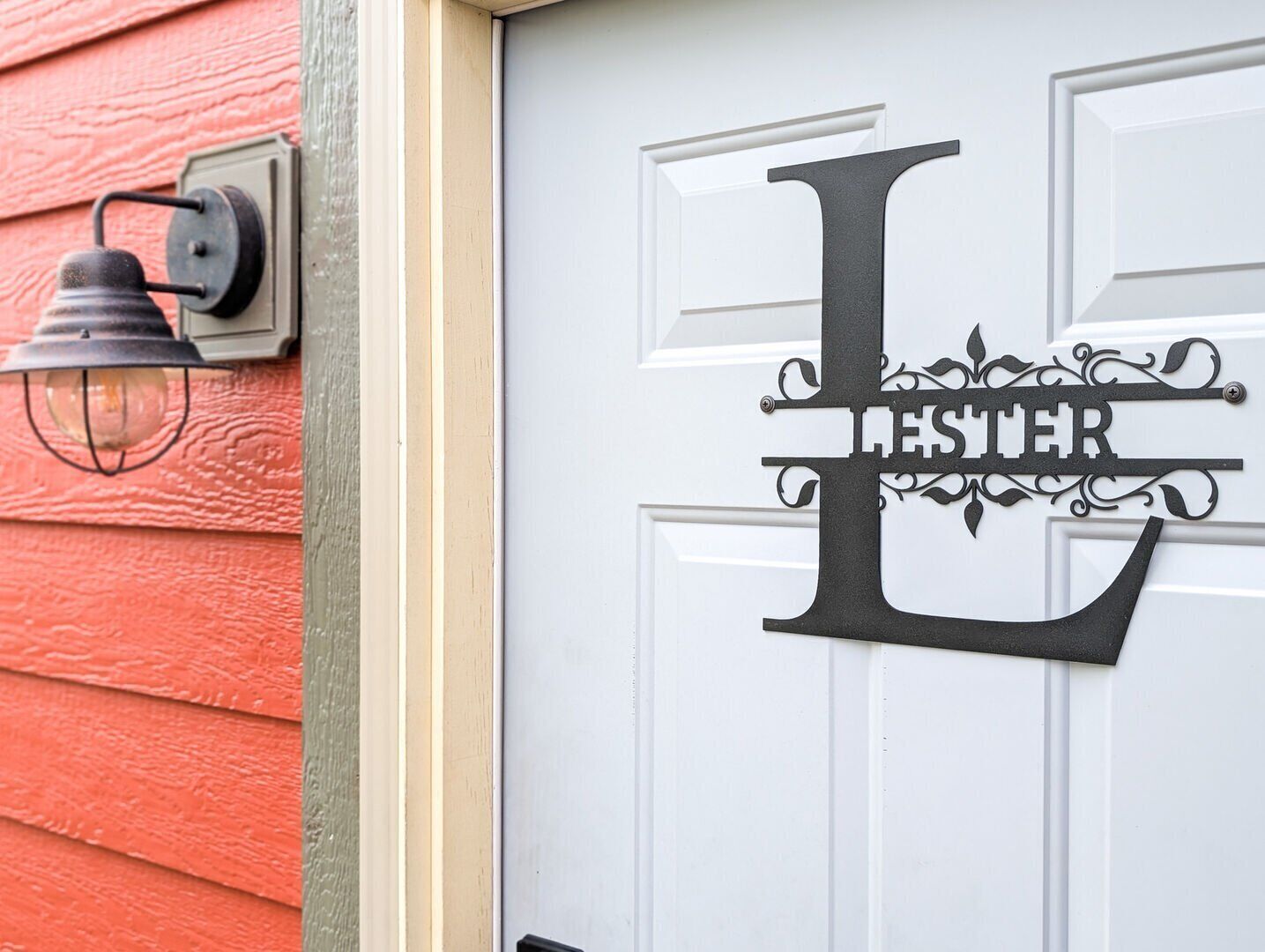 Una puerta blanca con una 'L' negra grande y el nombre 'Lester' en una tipografía decorativa.