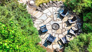 Un patio de piedra con una disposición circular de asientos y un brasero central.