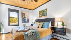 Ein Schlafzimmer mit einem großen Bett, einem Nachttisch, einer Lampe und Bildern an den Wänden.