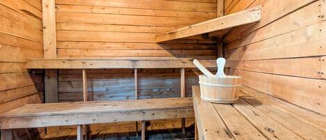 A wooden sauna with benches and a wooden bucket.
