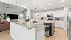 Une cuisine moderne avec des armoires blanches, un comptoir en granit et des appareils électroménagers en acier inoxydable.