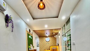 A hotel reception area with a reception desk, a brown leather sofa, a decorative light fixture, and a reception sign. - Hotel Green Plaza (Sonepat)