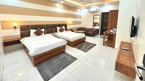 A modern hotel room with two beds, a sofa, a TV, and a desk. - Hotel Green Plaza (Sonepat)
