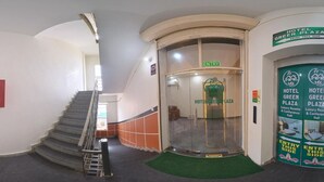A hotel entrance with a glass door, a staircase, and a green carpet. - Hotel Green Plaza (Sonepat)