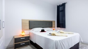 Una habitación de hotel moderna con cama, mesitas de noche y ventilador de techo.
