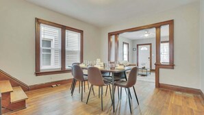 Un coin repas avec une table en bois, quatre chaises et un miroir au mur.