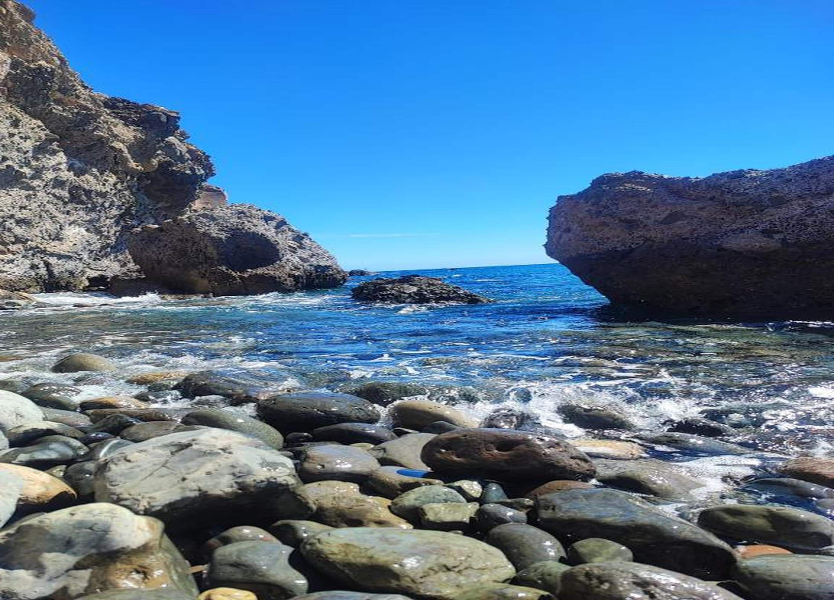 A rocky shoreline with clear water and a view of the ocean.
