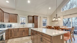 Una cocina amplia con armarios de madera, una isla grande y una zona de comedor con mesa y sillas.