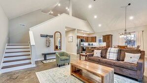 Amplia sala de estar con una mesa de centro de madera, un sofá de cuero marrón y un comedor con candelabro.