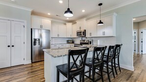 A modern kitchen with white cabinets, stainless steel appliances, and a central island with bar stools.