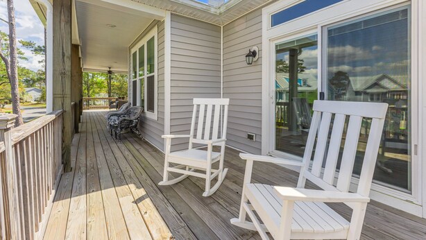 A wooden deck with two rocking chairs and a bench, overlooking a residential area.