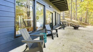 Una veranda riparata con poltrone Adirondack, un braciere e un muro in pietra.
