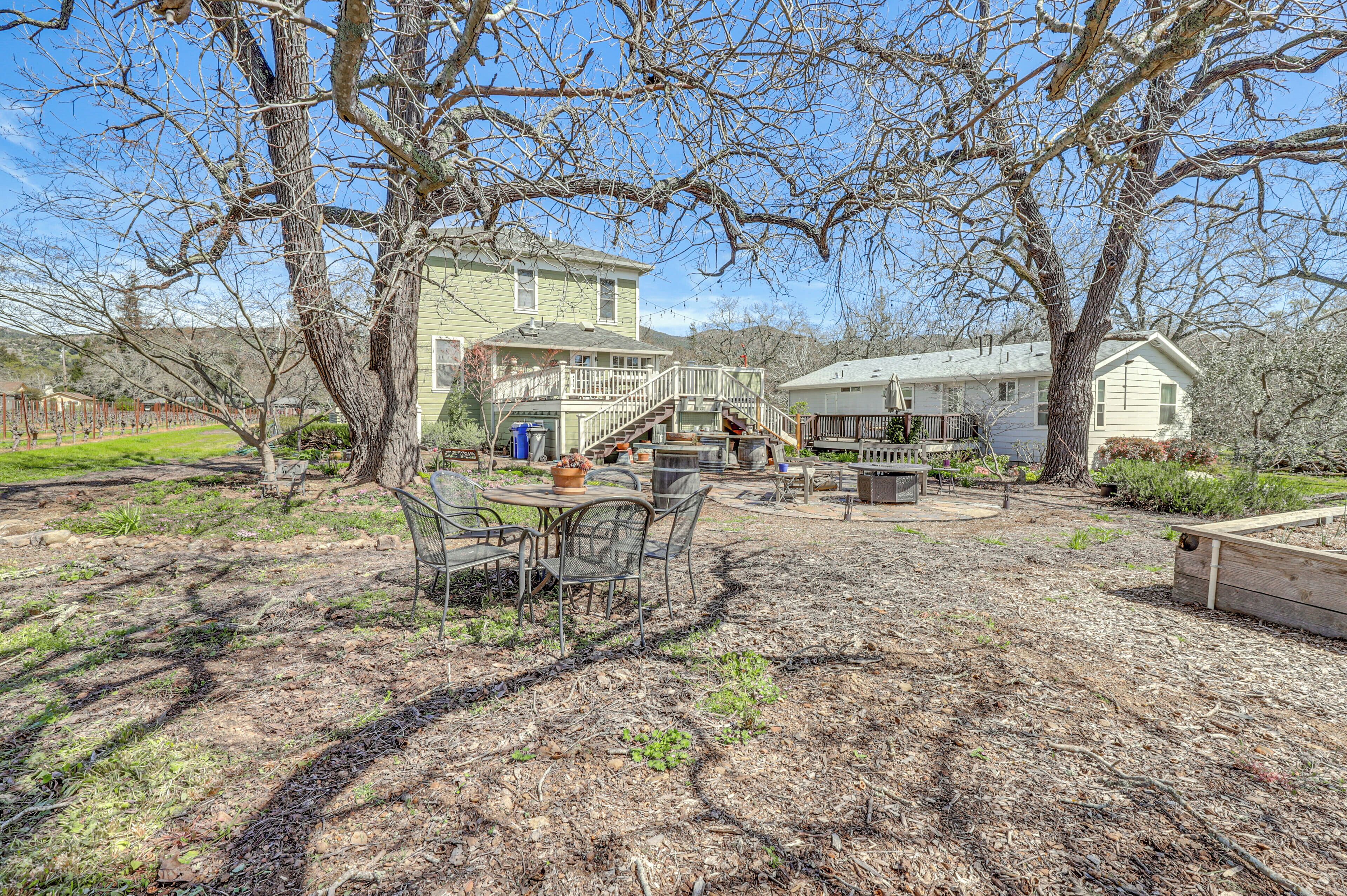 A backyard with a patio table and chairs, surrounded by trees and a house.