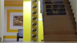 Un escalier avec des finitions en bois et un mur d’accent jaune.