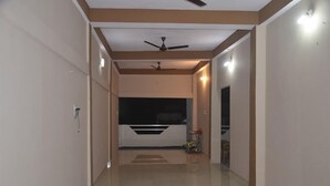 Un couloir avec un ventilateur de plafond, une armoire noire et blanche, et une petite table sur laquelle sont posés divers objets.