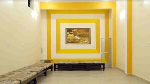 Une pièce avec un long banc le long d’un des murs, un tableau encadré sur le mur opposé et une échelle appuyée contre le mur.