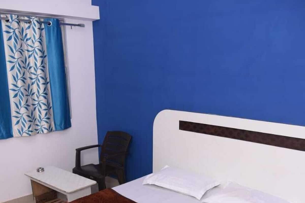Een slaapkamer met een bed, een bureau, een stoel en een blauwe wand.