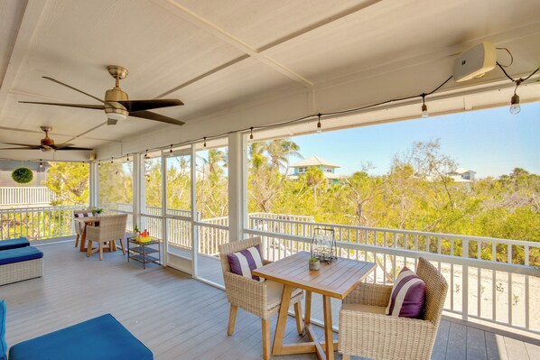 A covered outdoor area with wicker furniture, ceiling fans, and a view of the surrounding landscape. - Little Gasparilla Island Escape on Private Island! (Placida)