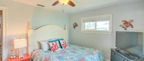 Un dormitorio con cama, cómoda, ventilador de techo, ventana y decoración mural.