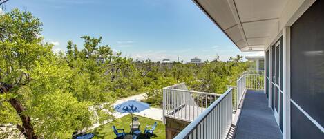A balcony with a view of a landscaped area, including a lawn and a pool.